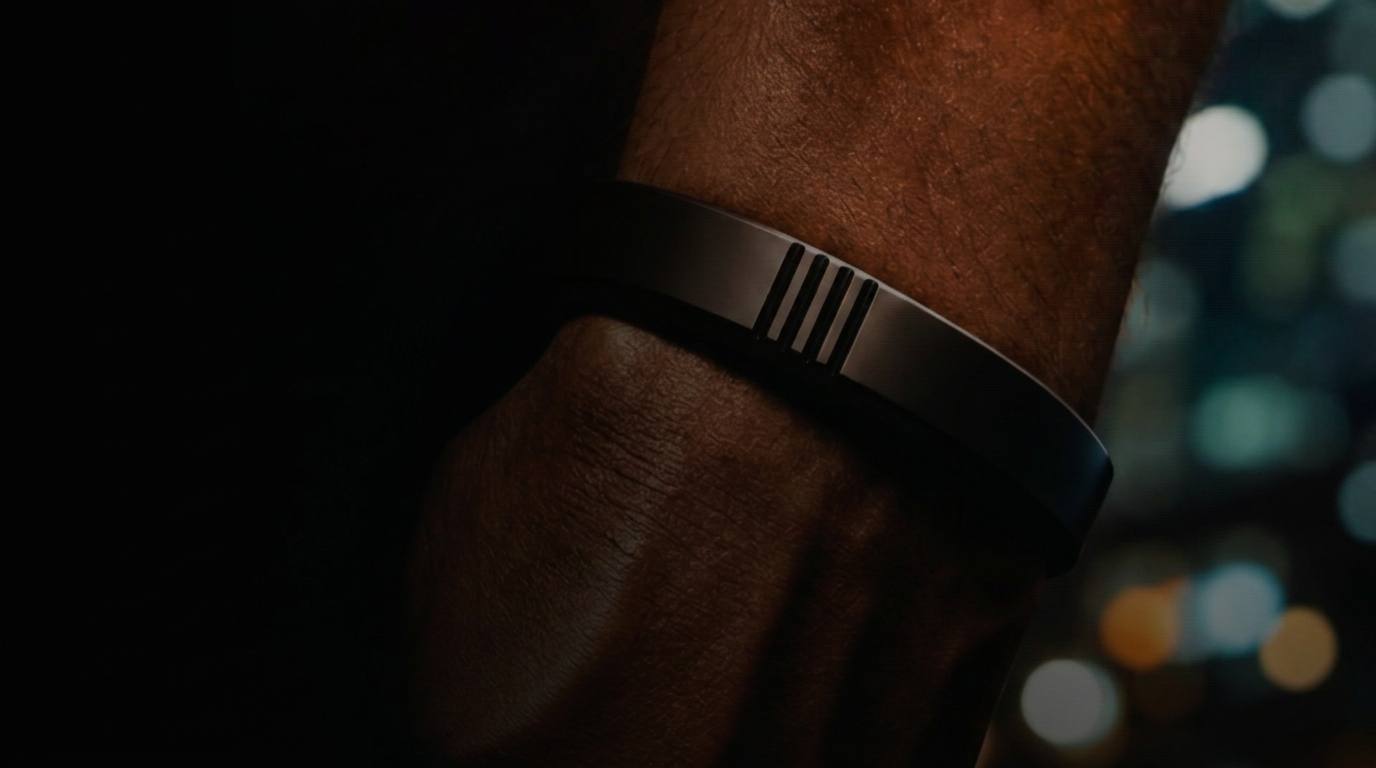 Close-up of a wrist wearing the matte black Rieset Bracelet on a city street at night